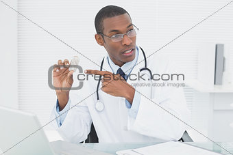 Doctor pointing at prescription bottle in medical office