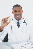 Smiling doctor holding a prescription bottle in medical office
