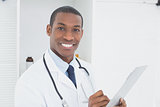 Smiling doctor writing a prescription in medical office