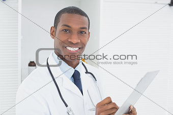 Smiling doctor writing a prescription in medical office