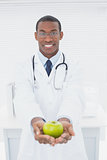 Male doctor holding a green apple at medical office