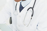 Mid section of doctor in lab coat and with stethoscope