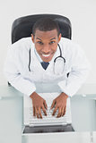 Overhead portrait of a smiling male doctor using laptop