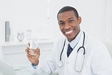 Smiling doctor holding a glass of water in medical office