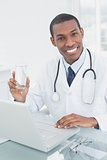 Male doctor holding a glass of water in medical office