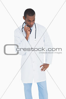 Serious thoughtful male doctor looking down
