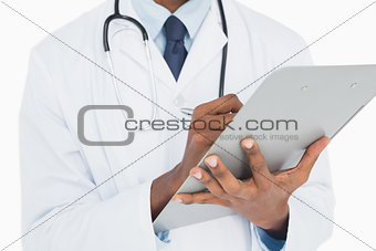 Mid section of a male doctor writing on clipboard
