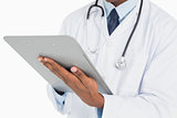 Close up mid section of a male doctor writing on clipboard