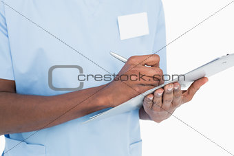 Mid section of a male surgeon writing on clipboard
