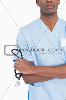Mid section of serious surgeon holding stethoscope