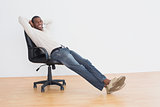 Smiling Afro man sitting on office chair in an empty room