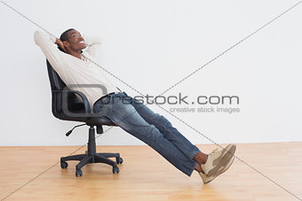 Thoughtful casual Afro man sitting on office chair in empty room