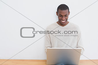 Afro young man using laptop on floor