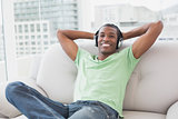 Relaxed young Afro man with headphones sitting on sofa