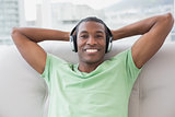 Relaxed Afro man with headphones sitting on sofa