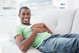 Casual smiling Afro man with digital tablet lying on sofa