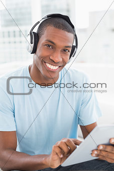 Afro man wearing headphones while using digital tablet