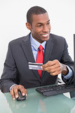 Smiling young Afro businessman doing online shopping