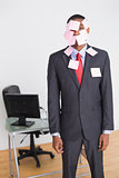 Businessman covered in blank notes at office