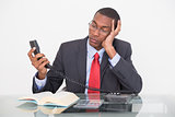 Tensed young Afro businessman looking at telephone receiver