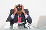 Frustrated Afro businessman with head in hands at  desk
