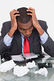 Frustrated Afro businessman with head in hands at desk
