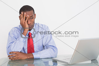 Thoughtful Afro businessman with hand on face at desk