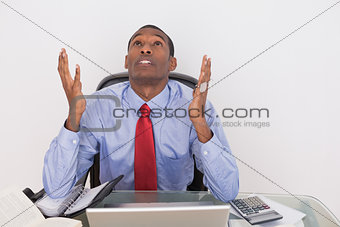 Serious Afro businessman looking up at desk