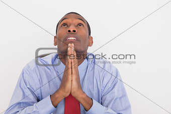 Serious Afro businessman looking up with joined hands