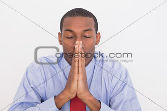 Afro businessman with joined hands and eyes closed