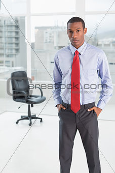 Elegant serious Afro businessman standing in office