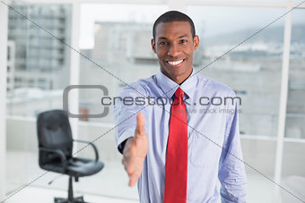 Elegant smiling Afro businessman offering handshake at office