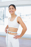 Smiling woman measuring waist in fitness studio