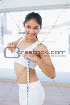 Smiling woman measuring chest in fitness studio