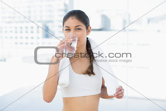 Woman with towel around neck drinking water