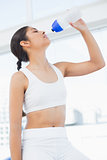 Young woman drinking water in fitness studio