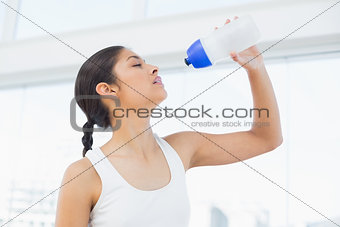 Fit woman drinking water in fitness studio