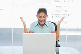 Happy businesswoman looking at laptop in office