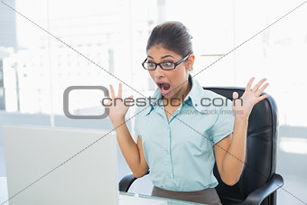 Shocked businesswoman looking at laptop in office