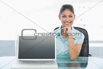 Elegant businesswoman displaying laptop in office