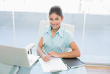 Businesswoman with laptop writing document in office