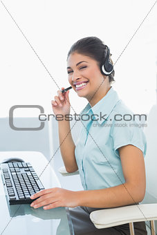 Cheerful businesswoman wearing headset while using computer