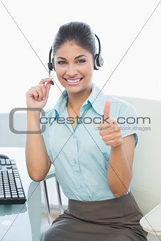 Businesswoman wearing headset while gesturing thumbs up
