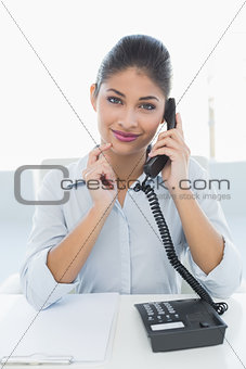 Elegant businesswoman using telephone at desk