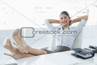 Relaxed businesswoman sitting with legs on desk in office