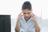 Tired businesswoman suffering from headache in front of computer