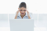 Businesswoman suffering from headache with laptop at office
