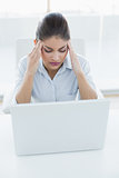 Businesswoman suffering from headache with laptop at office