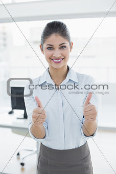 Smiling businesswoman gesturing thumbs up at office
