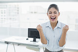 Happy businesswoman clenching fists in office